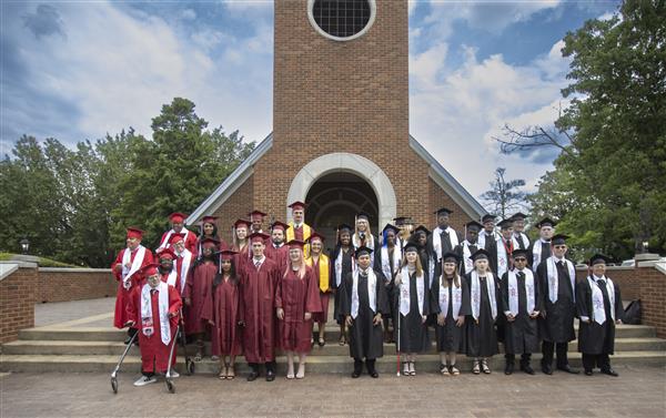 The class of 2024 from Helen Keller School of Alabama, Alabama School for the Deaf and Alabama School for the Blind stand on the front steps of Hawkins Chapel and smile to camera.